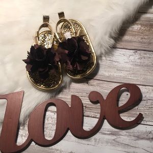 Gold Sandals with brown flower on top of toes.